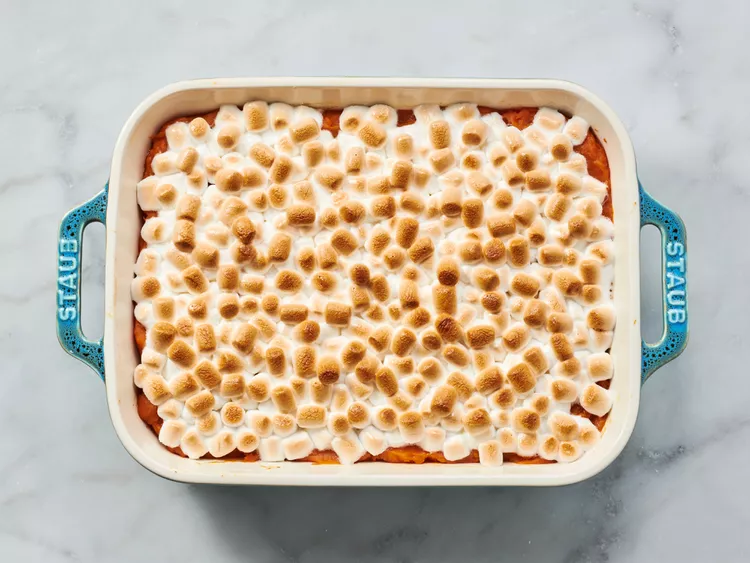 Close-up view of sweet potato casserole with melted marshmallows, showing the crispy topping and creamy texture inside.