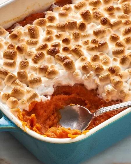 Ingredients for sweet potato casserole, including sweet potatoes, butter, brown sugar, eggs, milk, and marshmallows.